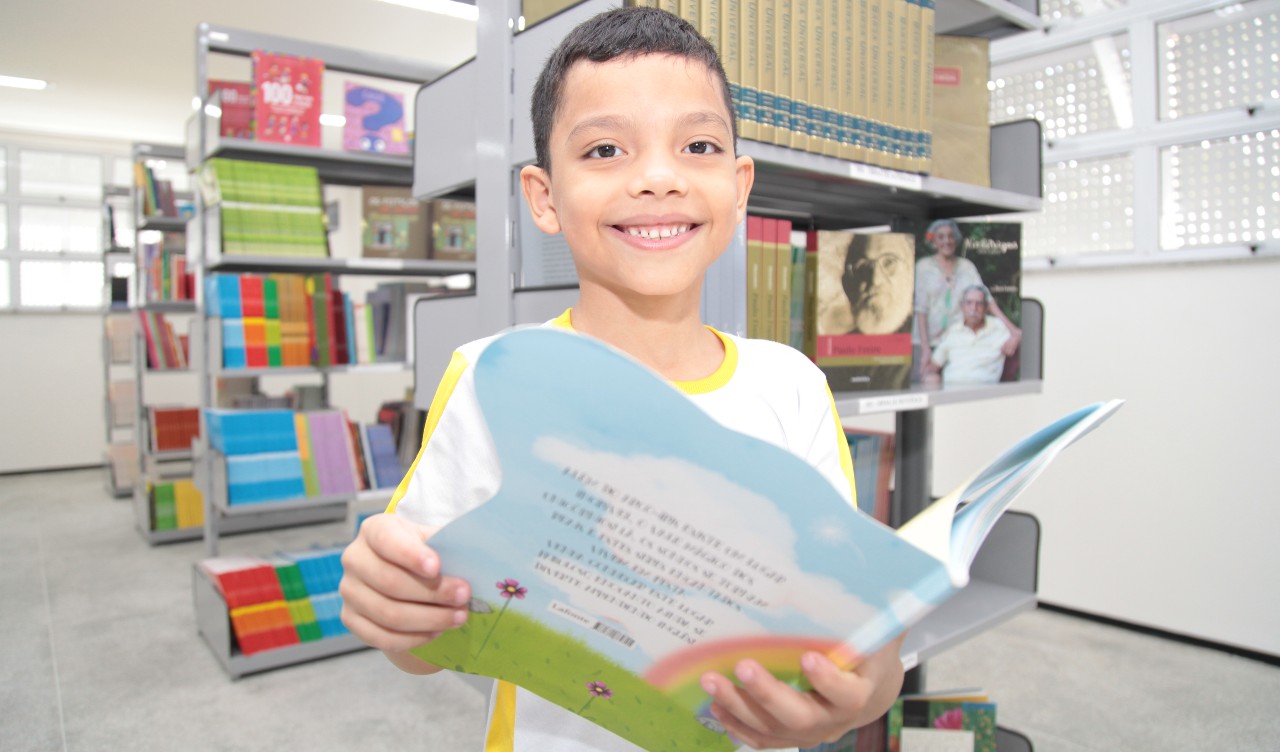 criança olha para a câmera enquanto segura um livro